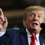 Donald Trump fala ao microfone e levanta o dedo indicador durante comício